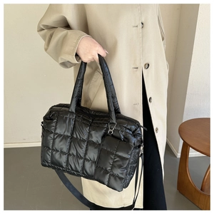 Close-up of black quilted puffer bag with detachable strap and mini zip pouch detail