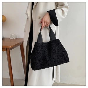Close-up of black fuzzy plush handbag with wide webbing handle for winter outfits