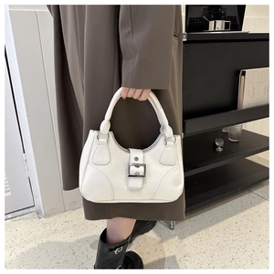 Detailed close-up of cream hobo handbag with silver buckle on a stylish model