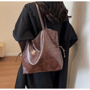 Deep brown oil wax leather tote bag shown on shoulder in a minimalist lifestyle setting