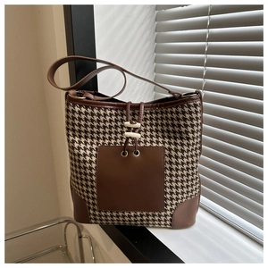 Close-up of houndstooth fabric texture and leather drawstring detail on bucket bag