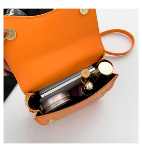 Internal view of orange leather saddle bag showing capacity for phone and cosmetics