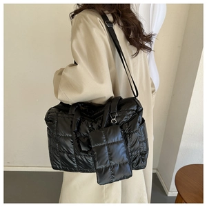 Detail of black quilted puffer tote bag with adjustable strap and small zipper pouch