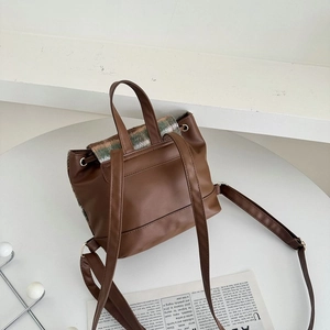 Detail view of brown backpack with colorful plaid flap and elegant PU leather straps