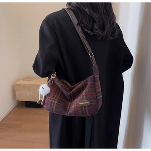 Detail of plaid shoulder bag with brown leather strap and cute white plush charm pendant