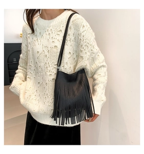Detail of black pebbled leather crossbody bag with long decorative tassels and slim strap