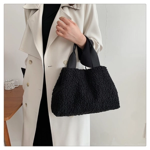 Close-up of black fuzzy lamb wool bucket bag with textured plush finish and wide fabric handle