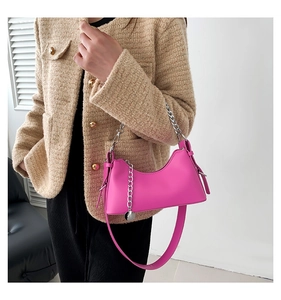Détail du sac sous le bras en forme de croissant rose vif avec chaîne argentée et cuir lisse