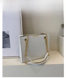 Detailed view of white crocodile pattern leather texture and gold chain strap on tote bag