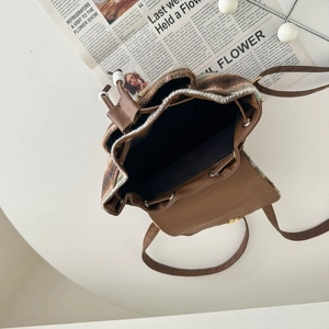 Detailed top view of wool plaid backpack with brown leather trim and drawstring closure