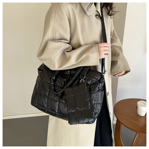 Detail of black quilted shoulder bag featuring glossy nylon texture and mini pouch