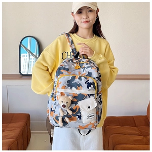 Detail view of stylish camouflage backpack with Fashion tag and plush bear accessory