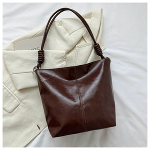 Detail of dark brown tote bag with glossy wrinkled leather and metal ring handle decoration