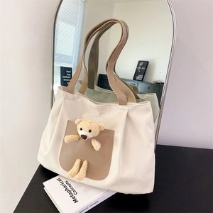 Detail of white canvas tote bag featuring a cute 3D plush bear on a brown front pocket