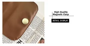 Detailed macro view of the golden magnetic buckle closure on a brown textured leather bag