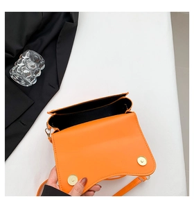 Top view of open orange leather saddle bag with magnetic closure and black lining