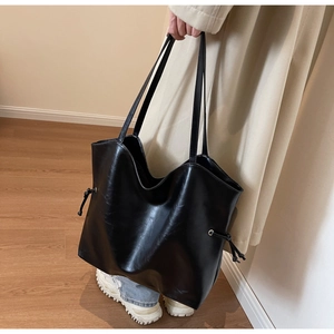 Detail of minimalist black tote bag with drawstring side knots and smooth finish