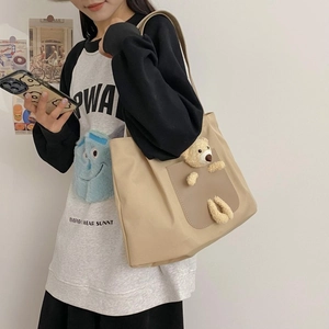 Close-up of khaki canvas tote bag featuring a cute 3D plush bear on the front pocket