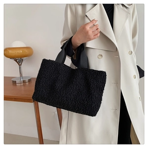Detail shot of the textured black fuzzy fleece tote bag carried by a model in a minimal setting
