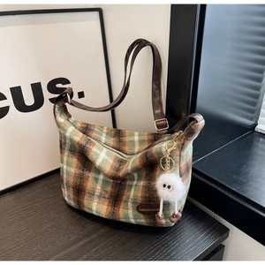 Detail of plaid tweed shoulder bag with leather strap and a cute white plush pendant