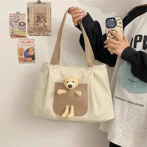 Detail view of cream canvas tote bag featuring a cute 3D plush teddy bear in leather pocket