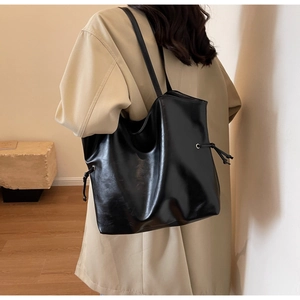 Detail of minimalist black bucket bag with side drawstring showing premium leather texture