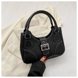 Detail of black leather handbag with white stitching and silver buckle in a lifestyle setting