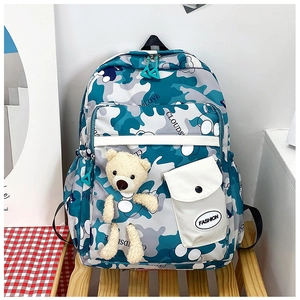 Detail of blue camouflage school backpack with fashion label and plush bear keychain