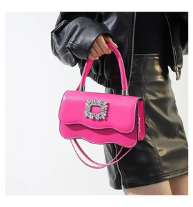 Détail du sac à main rose avec bords festonnés et une boucle carrée ornée de cristaux
