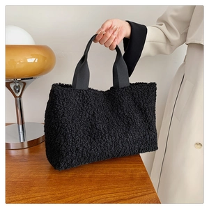 Detail of black faux shearling tote bag with textured plush finish and woven handle