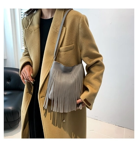 Detailed view of grey fringe leather shoulder bag with tassels on fashion model