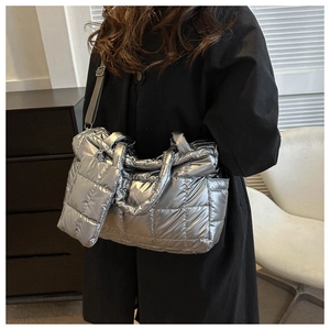 Detail view of quilted silver tote bag with mini pouch and adjustable strap on a model