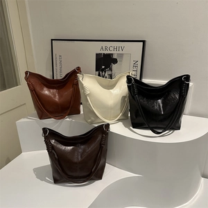 Minimalist faux leather tote bags in four colors displayed on a white tiered platform