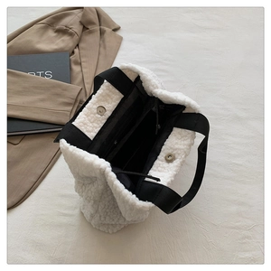 Detail view of white faux fur tote bag with magnetic metal clasp and black strap