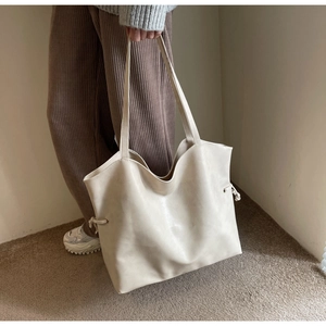 Detail of soft cream PU leather tote bag with side drawstring and textured finish