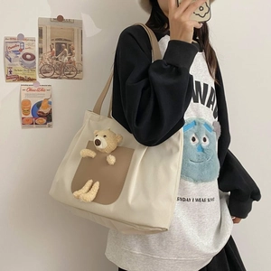 Close-up of cream canvas tote bag featuring a cute plush bear and brown leather pocket