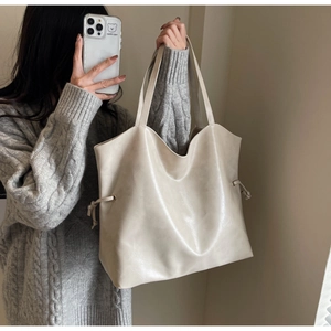 Detailed view of cream white bucket tote bag with drawstring on a model in knitwear