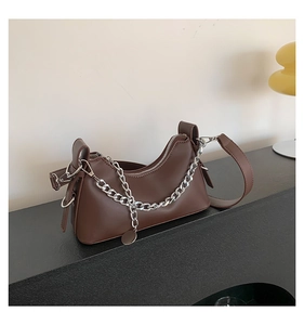 Détail du sac sous le bras en cuir marron foncé avec accessoire de chaîne argentée