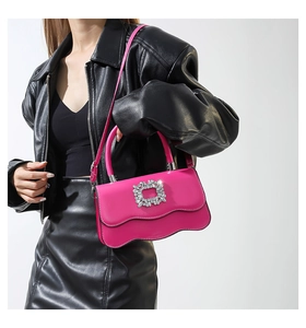 Détail du sac à main fuchsia brillant avec bord ondulé et boucle en cristal étincelant