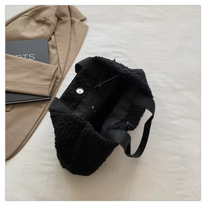 Detail view of black faux shearling tote bag showing inner zipper pocket and magnetic closure