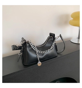 Détail du sac sous l'aisselle en cuir noir avec chaîne argentée et pendentif métal