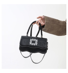 Détail du sac à main noir à bords ondulés avec boucle en cristal et cuir synthétique lisse