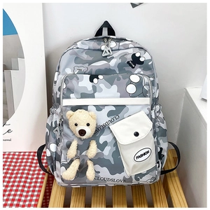 Detailed macro view of the grey camouflage pattern and plush bear charm on a large backpack