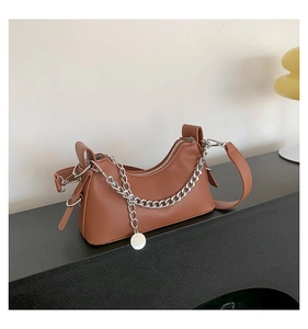 Détail du sac sous le bras caramel avec chaîne argentée et texture en cuir lisse