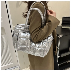 Silver quilted metallic tote bag with matching coin purse shown on a model shoulder