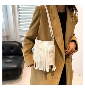 Detail view of white fringe shoulder bag in lychee leather on khaki winter coat