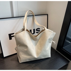 Detail view of large cream tote bag showing soft synthetic leather texture and drawstring side