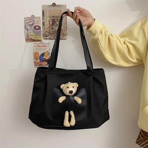 Detail of black canvas tote bag featuring a cute 3D plush bear decorative pocket