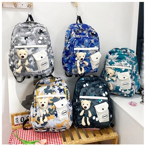 Detail showing five camouflage school bags in various colors with cute bear pendants