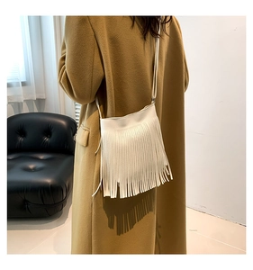 Rear view of a model wearing a white fringe crossbody phone bag with long tassels